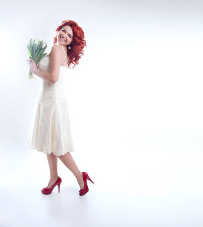 Beautiful redhead woman smiling, looking at camera. Attractive lady posing with white flowers.の写真素材