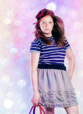 Fashionable young pretty girl posing over bright background, looking at camera の写真素材
