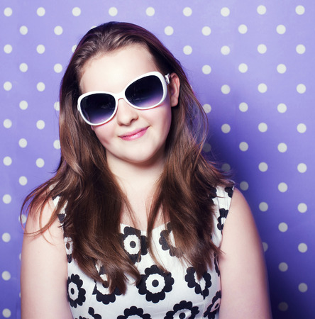 Young brunette pretty teenager girl posing over dots background, wearing sunglasses の写真素材