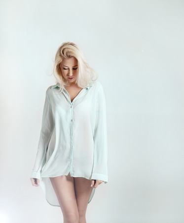 Sensual delicate blonde woman posing in studio wearing fashionable shirt.の写真素材