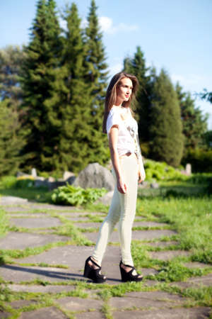 Fashionable brunette young beautiful woman posing on sunny day in park. Summer photo. Girl looking at camera.の写真素材