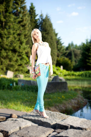 Fashionable blonde young beautiful woman posing on sunny day in park. Summer photo. Girl looking at camera.の写真素材