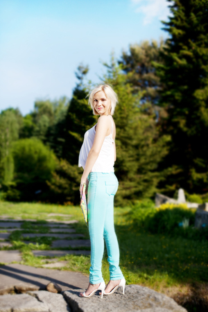 Fashionable blonde young beautiful woman posing on sunny day in park. Summer photo. Girl looking at camera.の写真素材