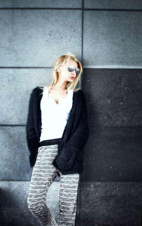 Young beautiful fashionable blonde woman posing over wall, wearing sunglasses.の写真素材