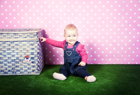 Cute little baby girl posing in studio over pink background.の写真素材