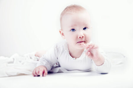 Cute little baby girl posing in studio over white background.の写真素材