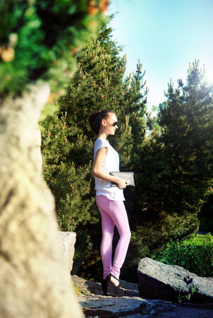 Young fashionable beautiful girl posing in sunny day in park, smiling.の写真素材