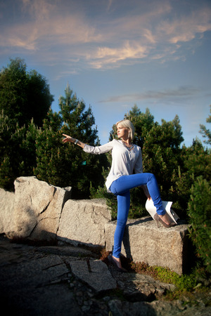 Young fashionable beautiful girl posing in sunny day in park, wearing blue jeans.の写真素材