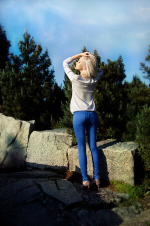 Young fashionable beautiful girl posing in sunny day in park, wearing blue jeans.の写真素材