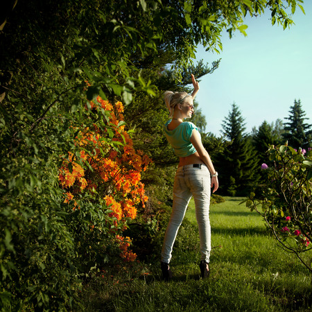 Sexy blonde woman posing over flowers on sunny day wearing fashionable clothes and sunglasses. Girl with slim perfect body.の写真素材