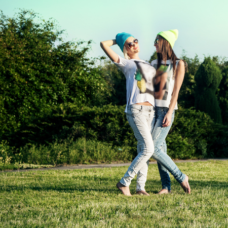 Two young beautiful girls posing outdoor in park, wearing fashionable clothes. Summer photo. Best friends.の写真素材