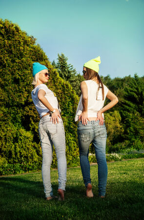 Two best friends having fun in park. Beautiful young girls posing, wearinf fashionable clothes. Summer photo.の写真素材