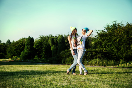 Two young beautiful girls posing outdoor in park, wearing fashionable clothes. Summer photo. Best friends.の写真素材