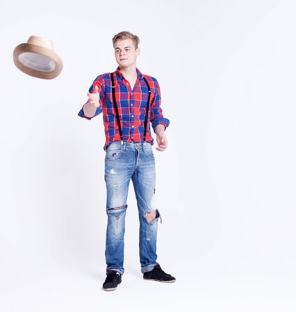 Handsome young fashionable man posing over white background with hatの写真素材