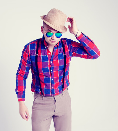 Fashionable handsome young man posing wearing hat and sunglasses. Studio photo. の写真素材