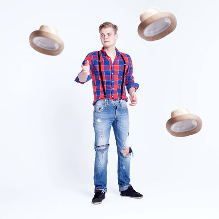 Handsome young fashionable man posing over white background with hatの写真素材