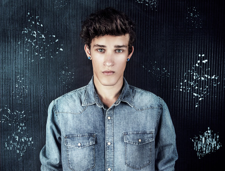 Young handsome male model posing wearing jeans fashionable clothes, studio shot. Man looking at cameraの写真素材