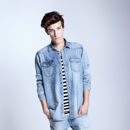 Young handsome male model posing wearing jeans fashionable clothes, studio shot. Man looking at cameraの写真素材