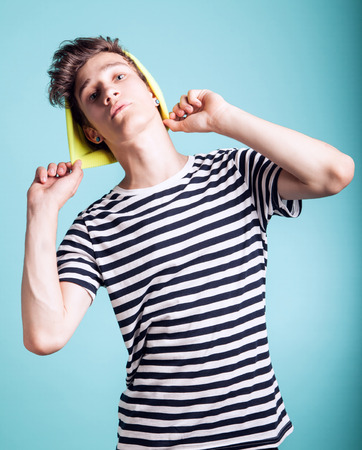 Young fashionable handsome guy posing wearing cap. Studio photo. Blue background.の写真素材
