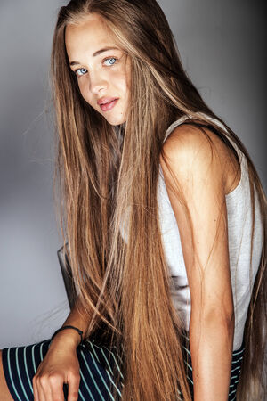Natural young beautiful girl posing in studio over gray backgroundの写真素材