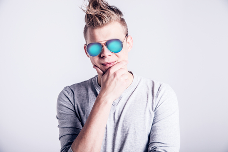Handsome young man posing in vreative hairstyle and sunglassesの写真素材