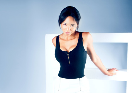 Beautiful young brunette woman posing in studio, wearing fashionable clothes, looking at cameraの写真素材