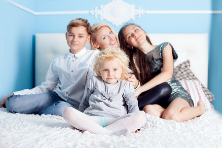 Family time, mother with three children relaxing in bed, looking at cameraの写真素材