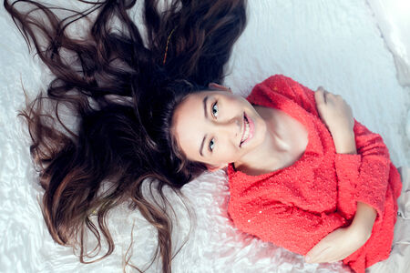 Young teenage girl lying in bed, relaxing, looking at camera and smilingの写真素材