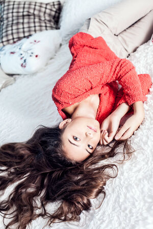 Young teenage girl lying in bed, relaxing, looking at camera and smilingの写真素材