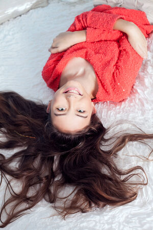 Young teenage girl lying in bed, relaxing, looking at camera and smilingの写真素材