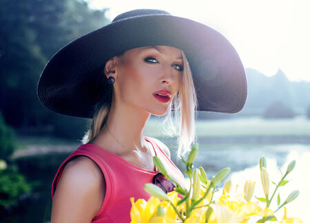 Beauty portrait of attractive sensual blonde woman wearing hat, posing outdoor in sunny dayの写真素材