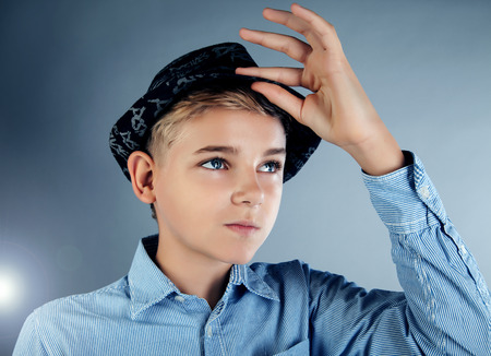 Handsome young teenage boy posing in studio with fashionable hatの写真素材