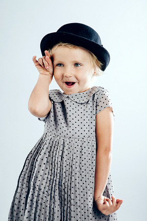 Little pretty blonde girl posing in fashionable hat in studioの写真素材