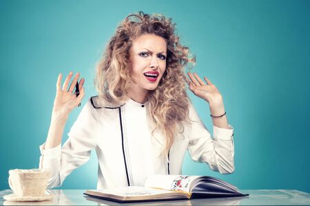 Attractive businesswoman at work. Girl with blonde long curly hair. Blue background.