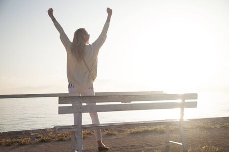 Happy young beautiful woman enjoying romantic sunrise over the ocean. Summer photo.