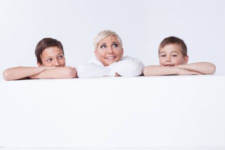 Family photo. Beautiful blonde mother posing with two young boys, looking at camera.の写真素材