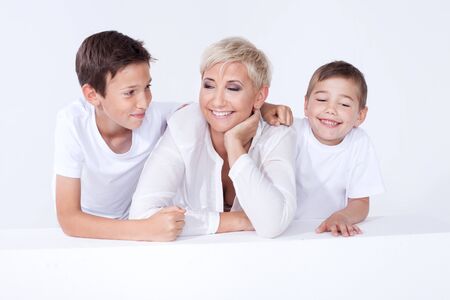 Family photo. Beautiful blonde mother posing with two young boys, looking at camera.の写真素材