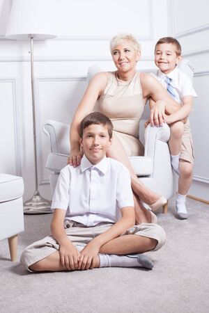 Family photo. Beautiful blonde mother posing with two young boys, smiling.の写真素材