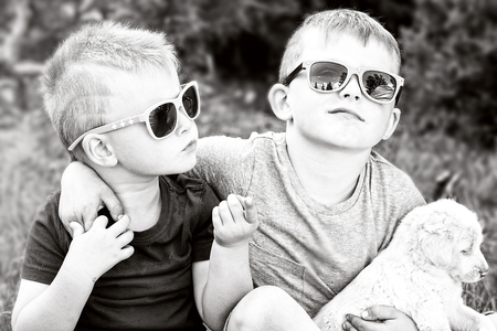 Two boys having fun with puppies. Summer time. Outdoor photo.の写真素材