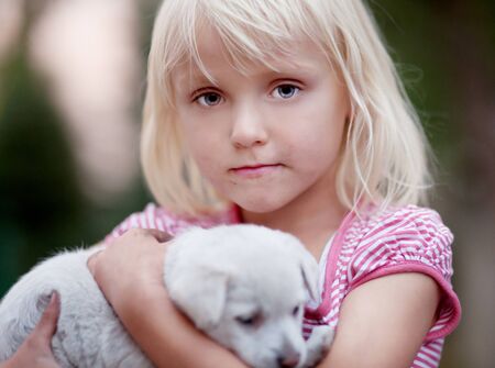 Little girl holding cute small puppy. Summer day. Sunset.の写真素材