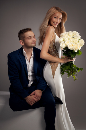 Beautiful wedding couple. Blonde woman in white dress and handsome man in suit. Love content.の写真素材