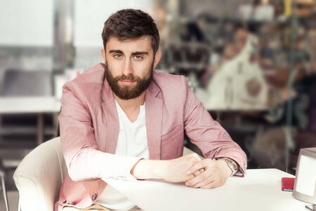 Handsome young elegant man sitting, relaxing, smiling. Men with beard looking at camera. Indoor photo.の写真素材