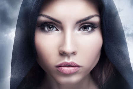 Closeup beauty portrait of attractive young woman with beautiful brown eyes. Hood on head. Brunette girl. Studio shot.の写真素材