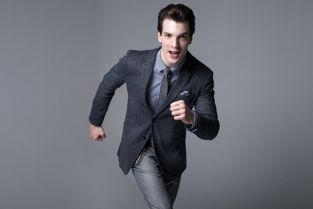 Running businessman. Studio shot. Succesfull young handsome man in elegant suit.