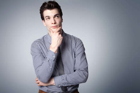 Young handsome businessman posing in studio, showing conceptual gesture, thinking. Elegant style.