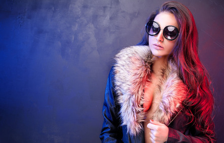 Fashionable sexy brunette girl posing in black leather jacket and sunglasses. Studio shot. Smoke.の写真素材