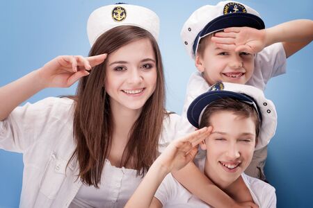 Family having fun, Brothers and sister wearing captain hat. Blue background.の写真素材