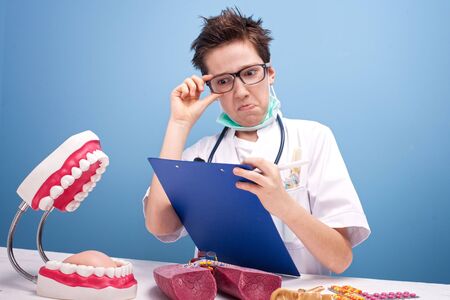 Young boy playing a dentist. Conceptual photo. Blue background.