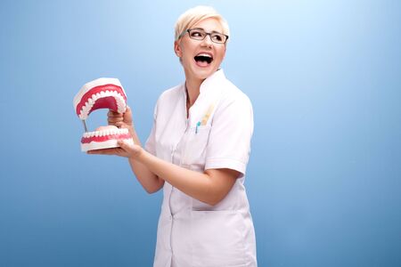 Professional doctor. Dentist woman with jaw posing on blue background.
