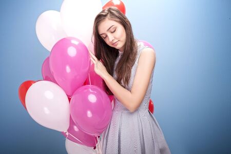 Young beautiful teenage girl posing in studio with balloons, looking at camera.の写真素材